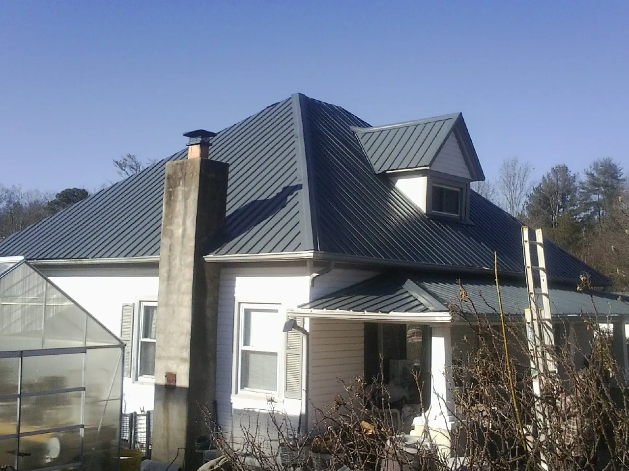 Dark blue standing seam metal roof on a white farmhouse with dormer — Slate & Tile Roof Repair by Roofing Brothers in Geyserville