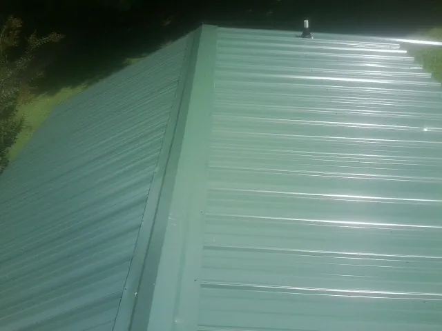 New green metal panels meeting at the ridge of a roof — Flat Roof Repair work by our crew in Geyserville