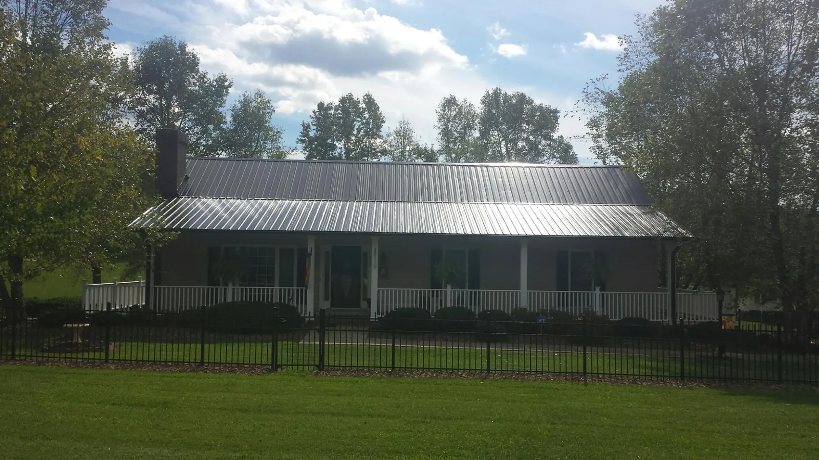 Gray metal roof on a brick ranch with a full width front porch — Gutter Guard Installation work by our crew in Geyserville