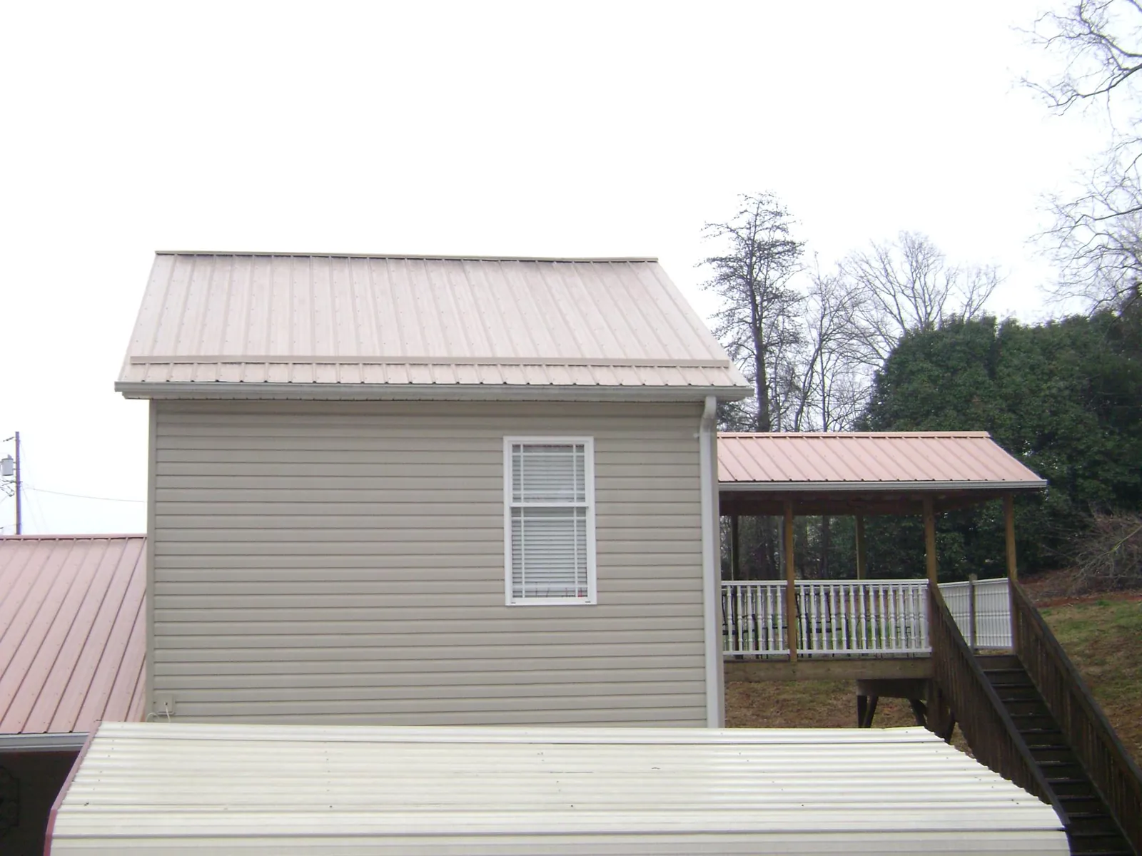 Tan metal roofs on a two story addition and attached porch, from a Roof Replacement job in Geyserville