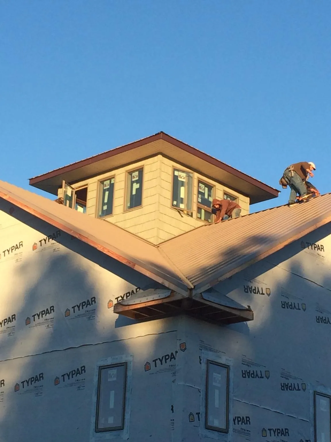 Roofers working around a rooftop cupola on a new metal roof at sunset — Roof Waterproofing in Geyserville by Roofing Brothers